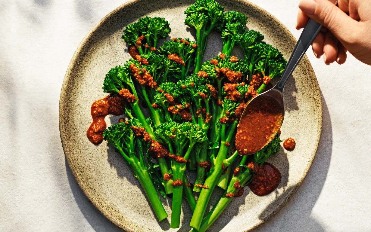 Ångad broccoli på en tallrik med dressing över