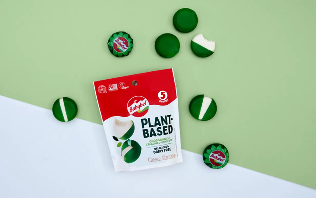 En förpackning växtbaserade ostar från Babybel på en grön och vit bakgrund, bild tagen uppifrån.