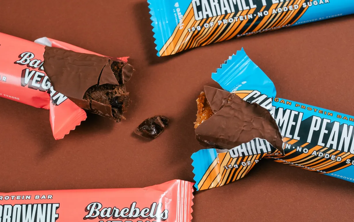 Fyra veganska proteinbars på ett brunt bord