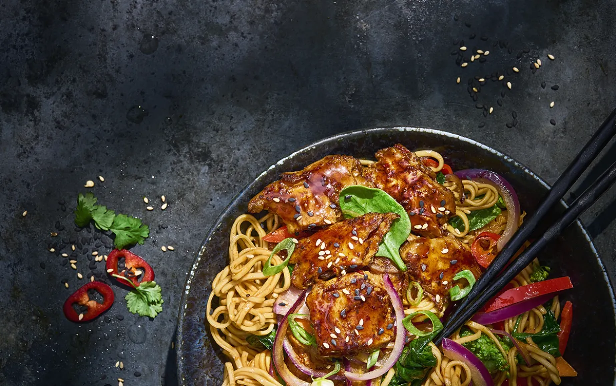 Koreansk nudelwok i en svart tallrik på ett svart bord