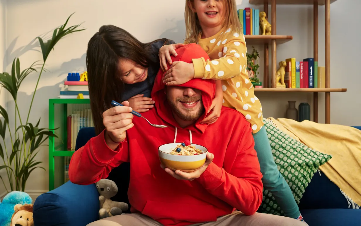 En man, en kvinna och ett barn som äter gröt i en soffa