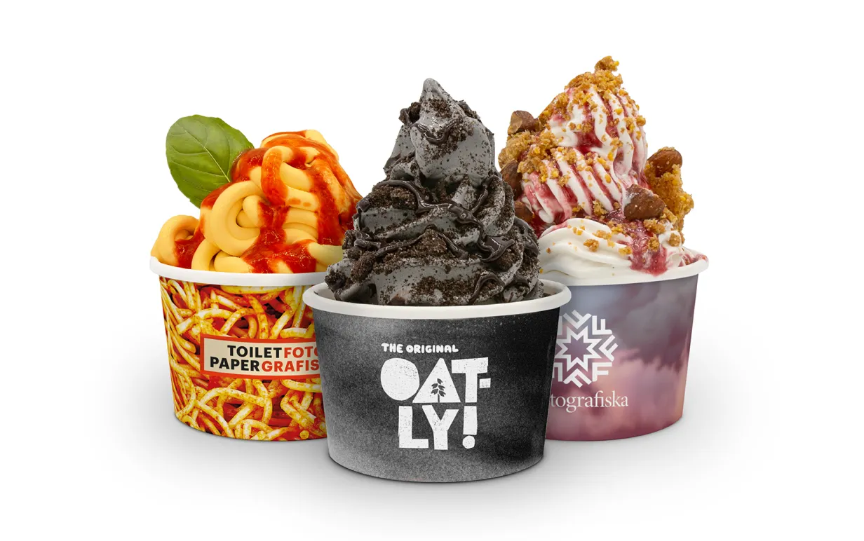 Tre veganska mjukglassar i olika färger i bägare mot en vit bakgrund