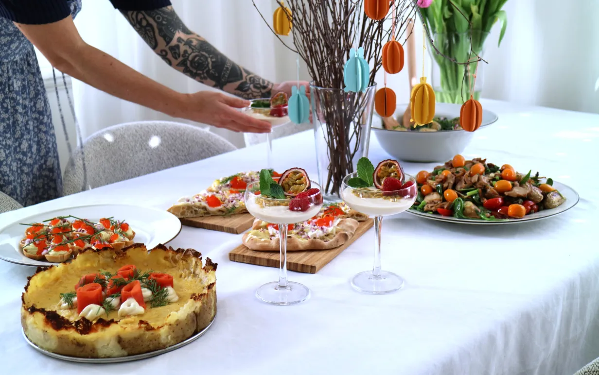 Veganskt påskbord och tjej med en tatuerad arm som håller i cocktailglas