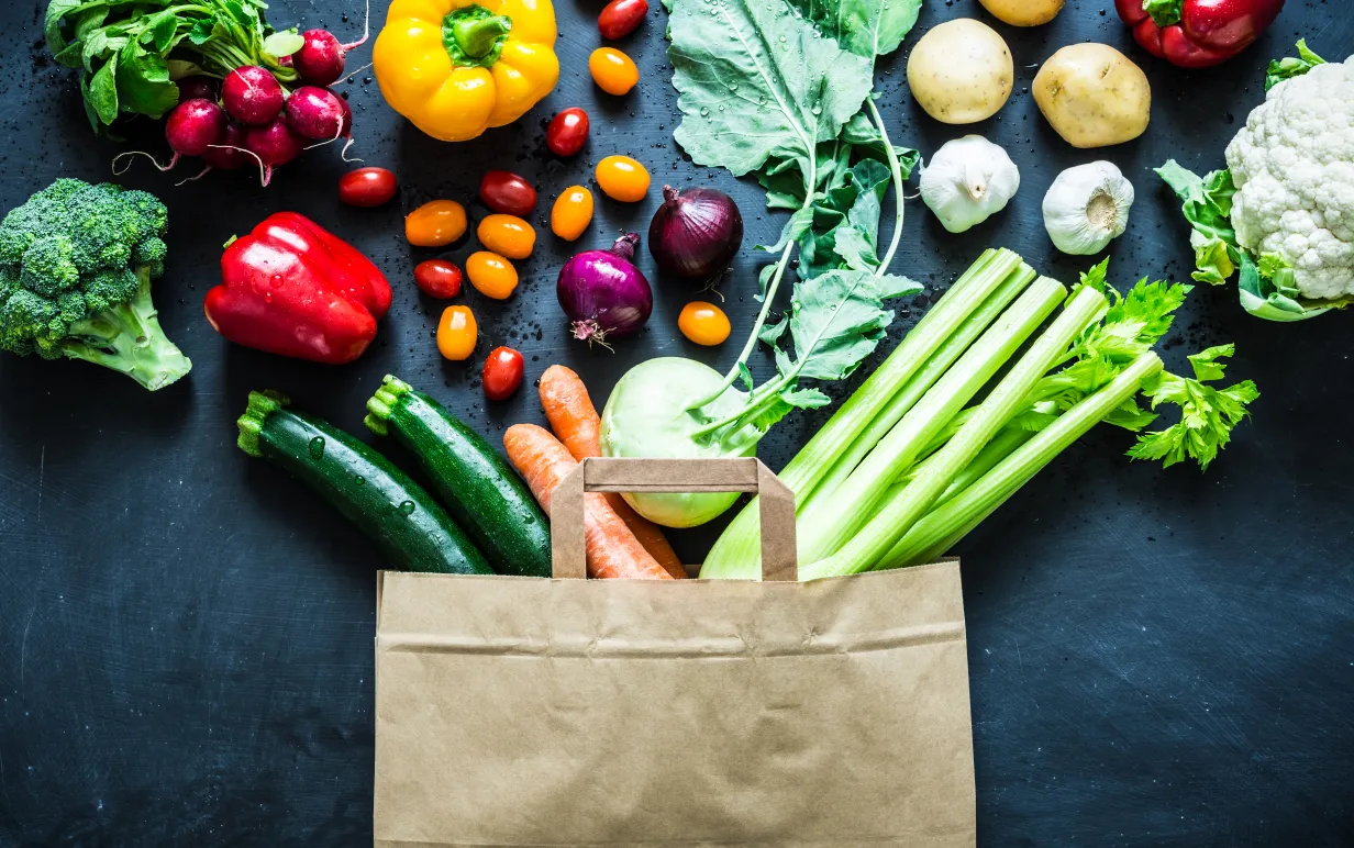 Bild på liggande matkasse där flera grönsaker ligger omkring