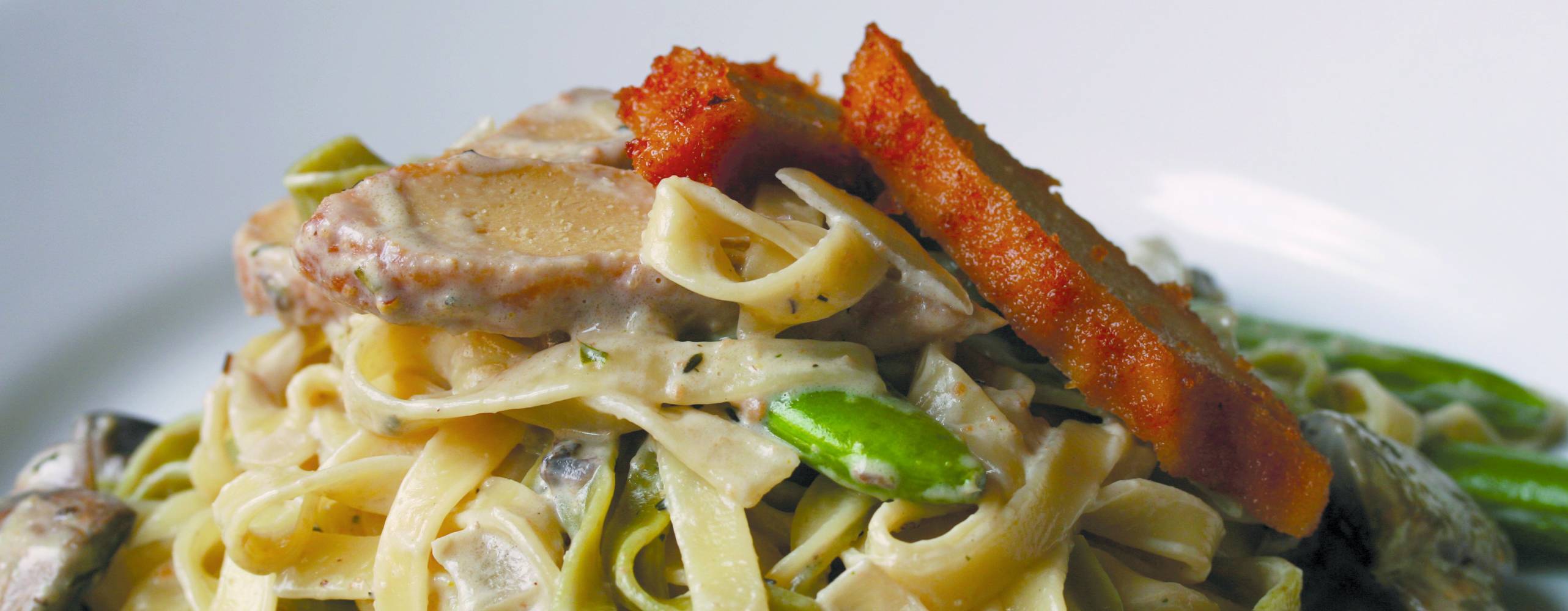 Pasta med sojakyckling Pasta med sojakyckling och sockerärtor på en vit tallrik