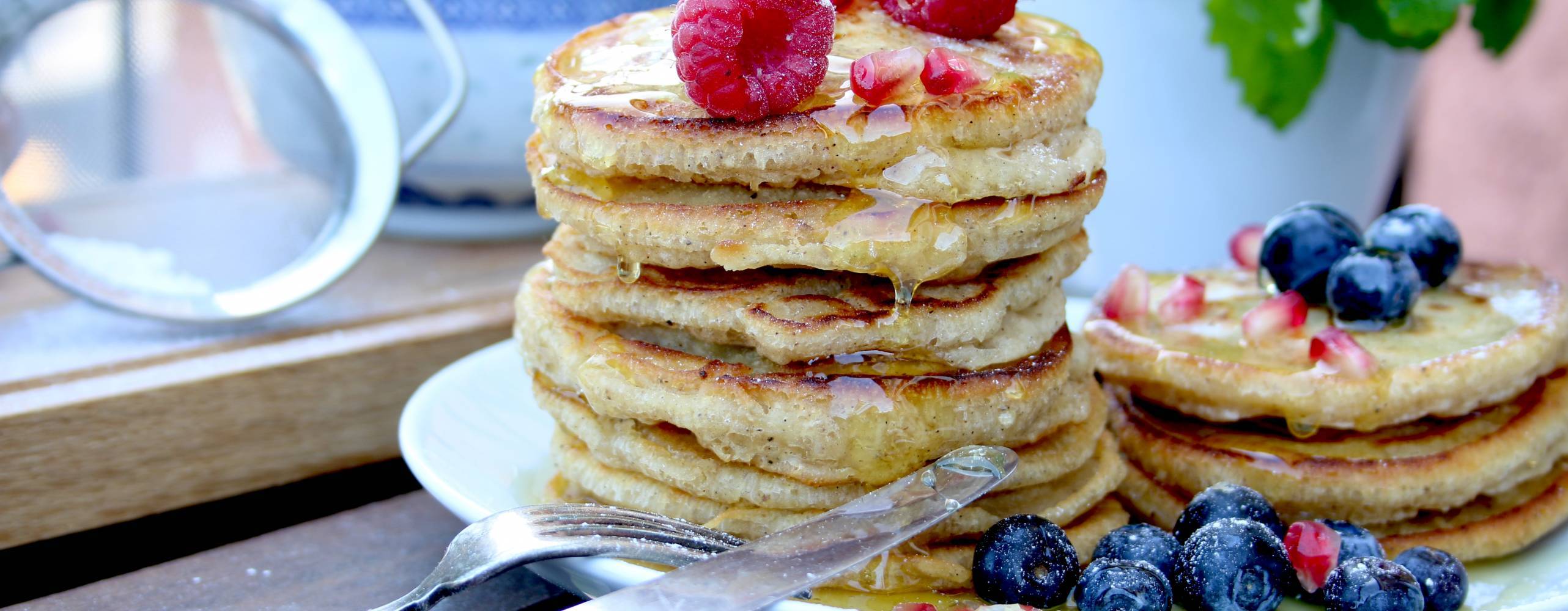 Veganska amerikanska pannkakor Veganska amerikanska pannkakor på en vit tallrik toppade med färska blåbär och hallon.
