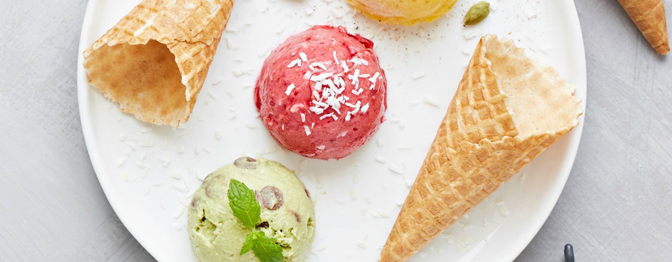 Hallon nicecream tre glasskulor med olika smak och två strutar på en vit tallrik