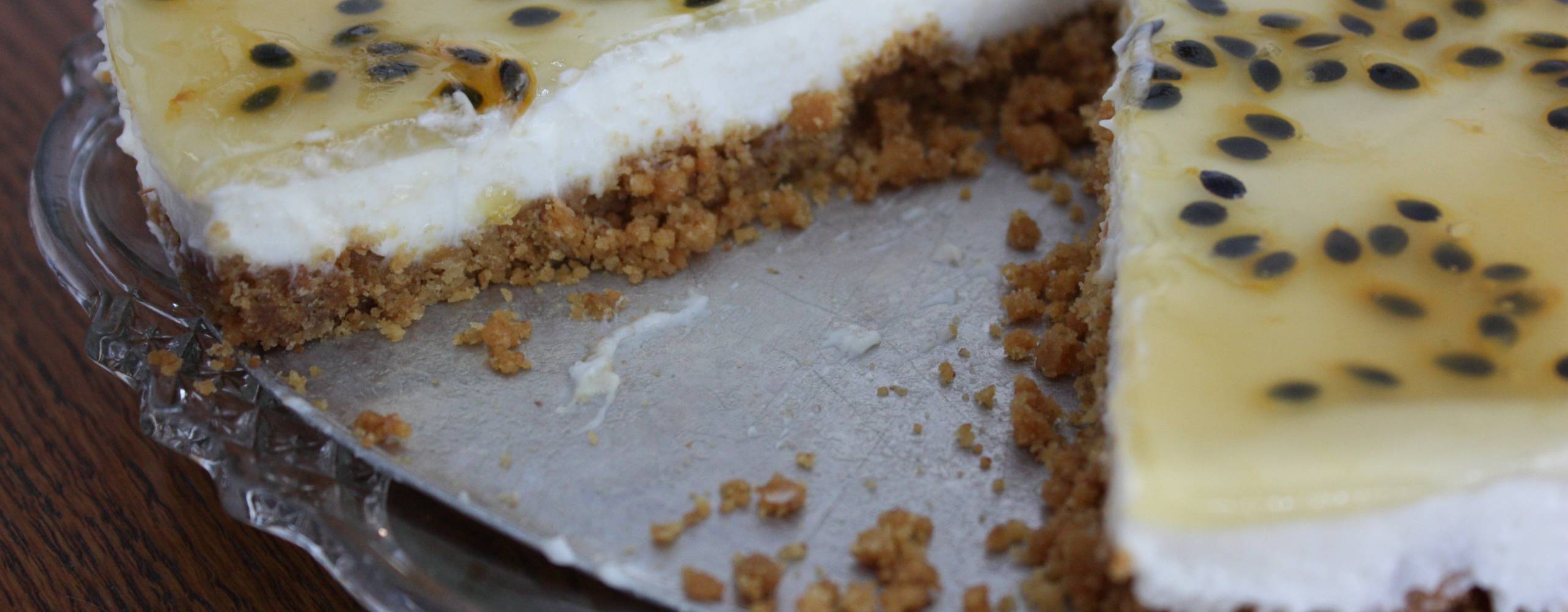 Citroncheesecake med passionsfrukt på ett tårtfat.