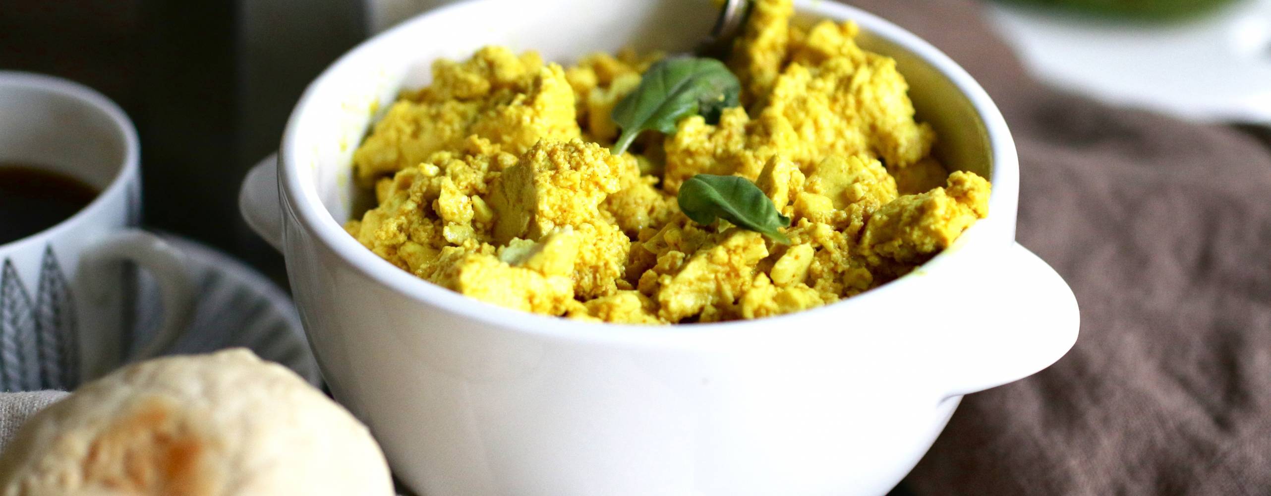 Scrambled tofu i en vit skål på ett bord.