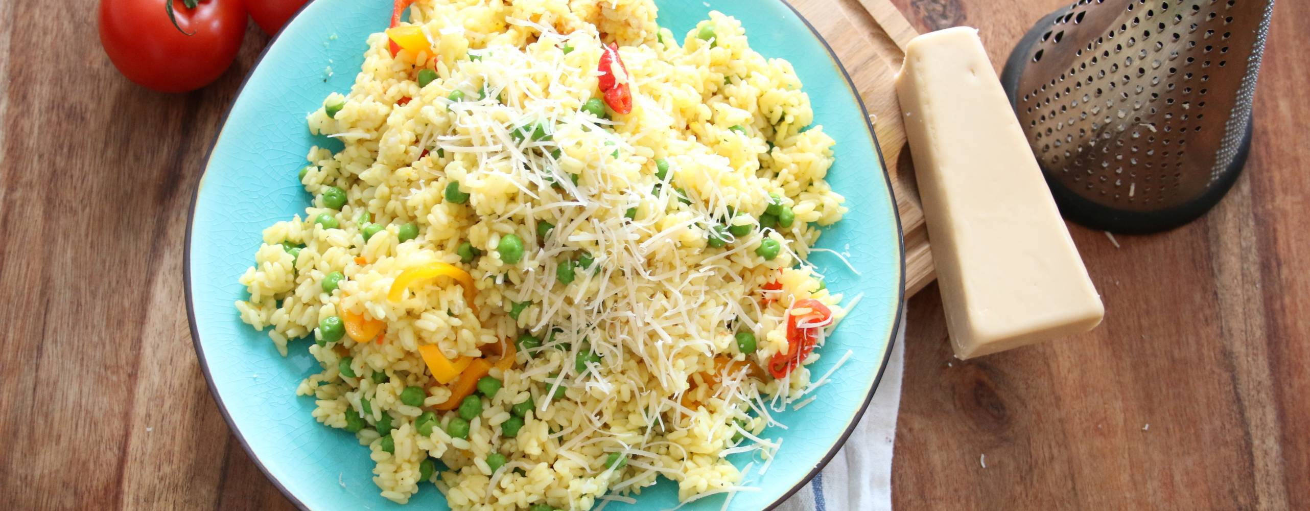 Risotto med gröna ärtor Risotto med gröna ärtor på en turkos tallrik, bredvid tallriken ligger en vegansk parmesanost och några tomater