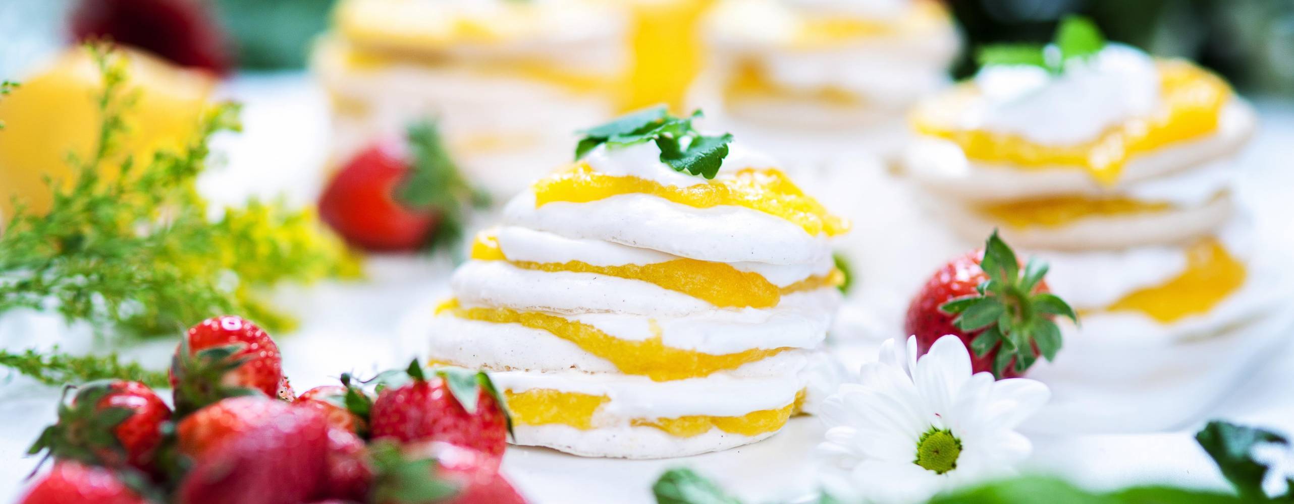 Marängtårta med mango curd, dekorerad med jordgubbar och citronmeliss.