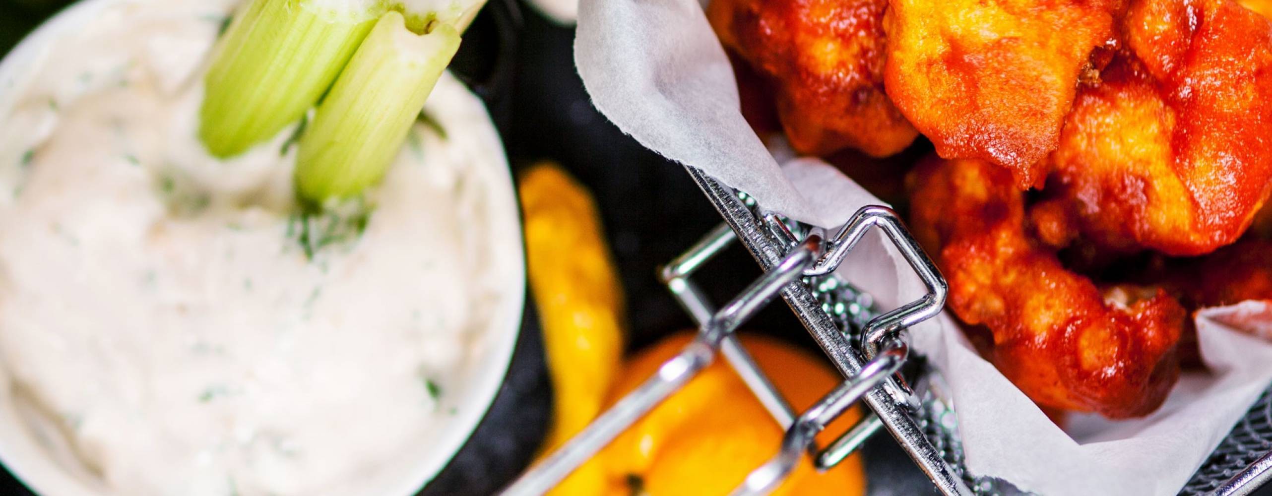 Buffalo wings av blomkål Buffalo wings av blomkål i en frityrkorg, bredvid står en skål med blåmögelostsås