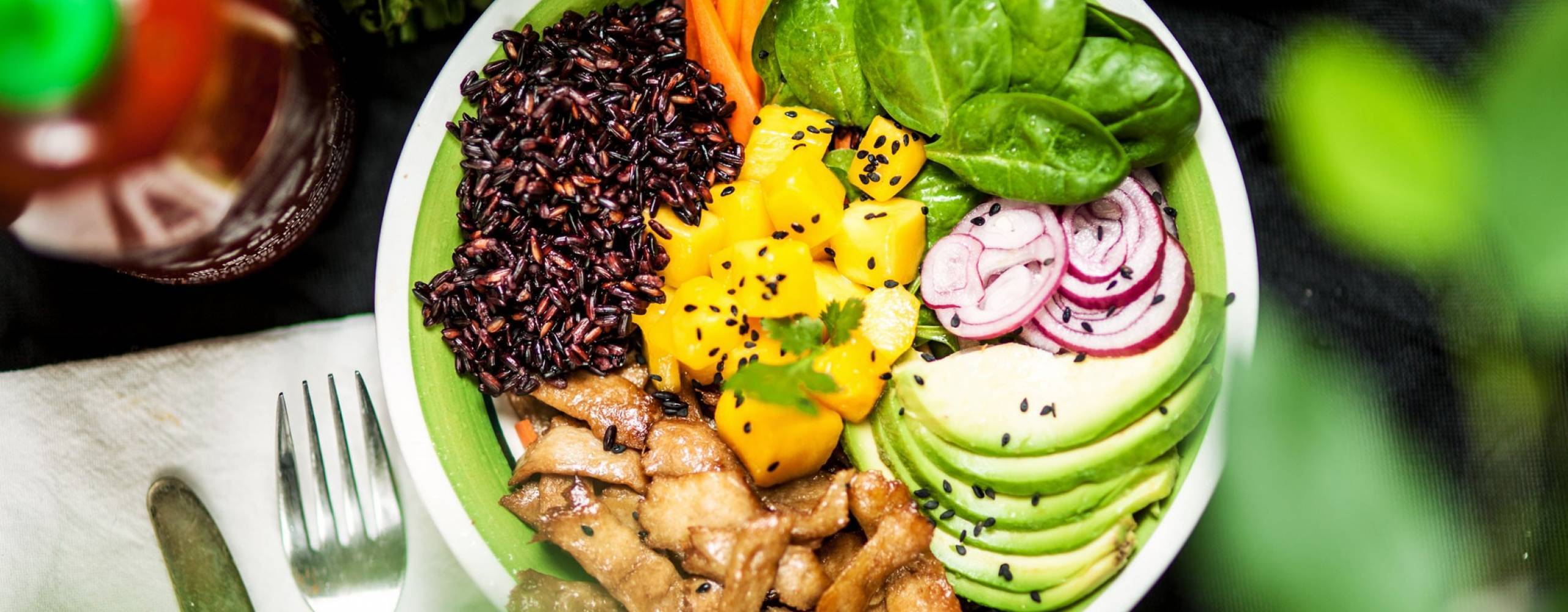 En pokébowl med babyspenat, mangobitar, vegobitar, svart ris och avokado.