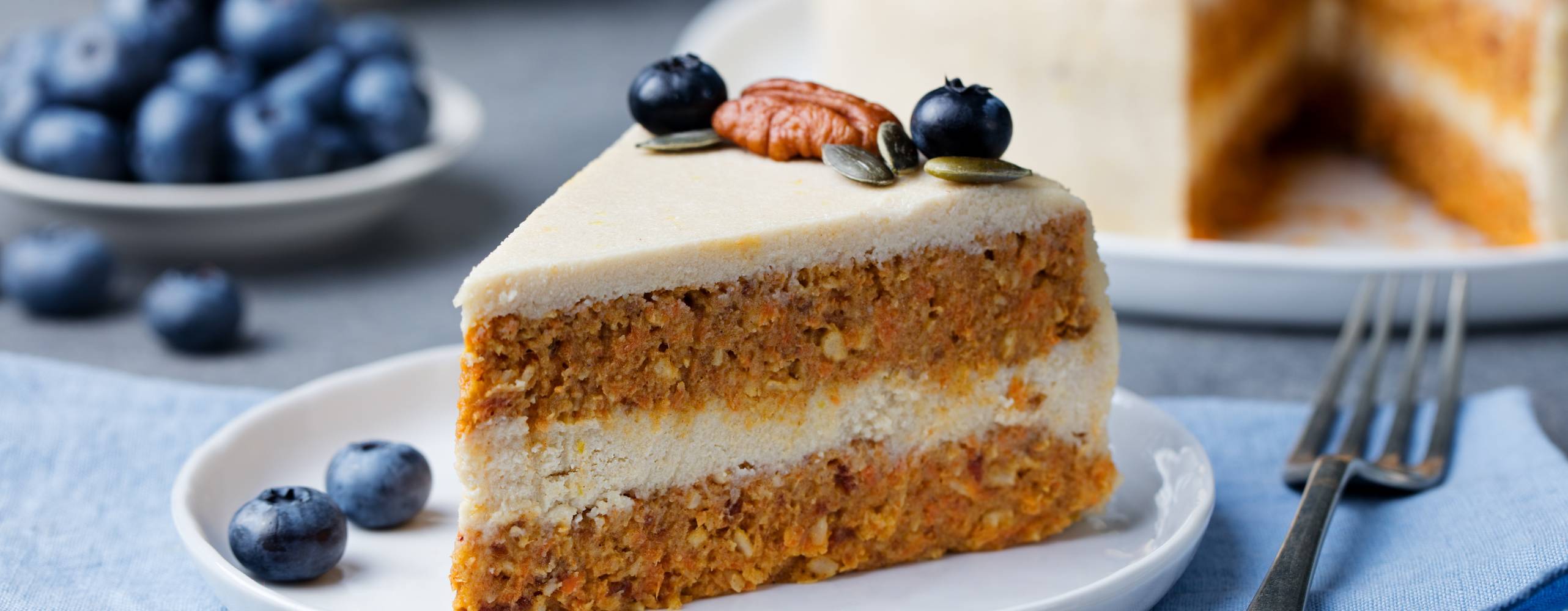 Vegansk morotskaka Vegansk morotskaka på en vit tallrik, bredvid tallrik ligger några blåbär