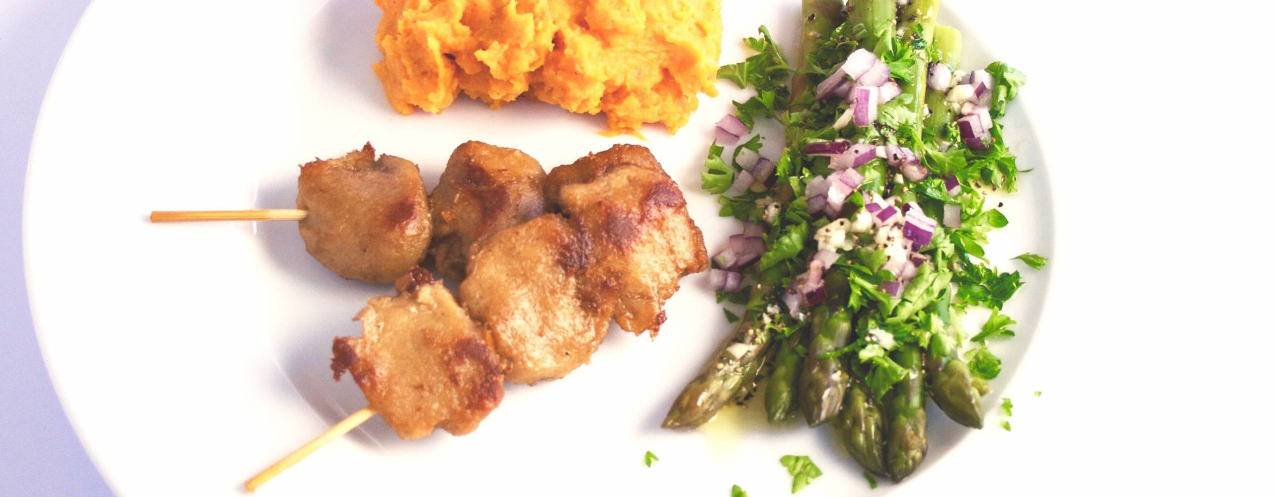 två tzayspett, sötpotatispuré och sparris på ett vitt fat