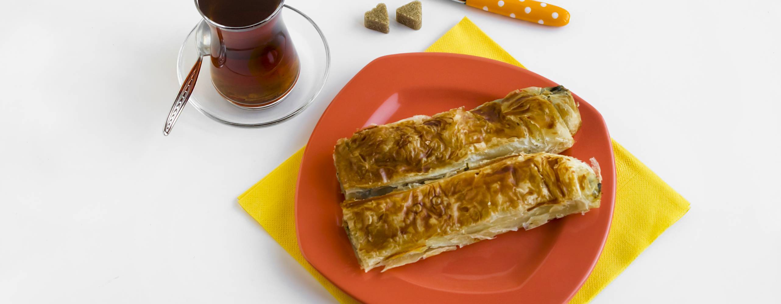 vegan börek på en orange tallrik, bredvid står ett glas med te