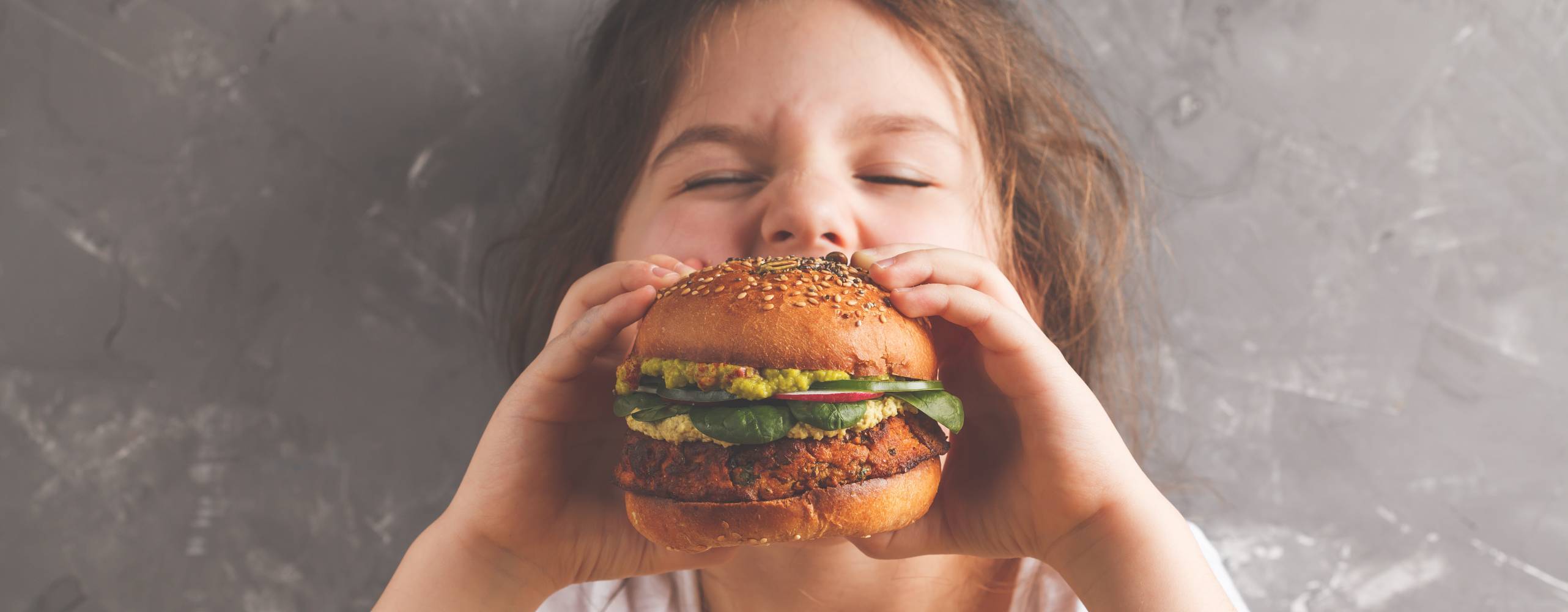 Shutterstock - Nina Firsova Ung barn äter hamburgare