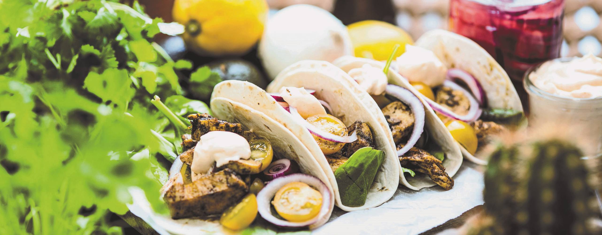 Fyra tortillas fyllda med veganska bitar och grönsaker på ett bord