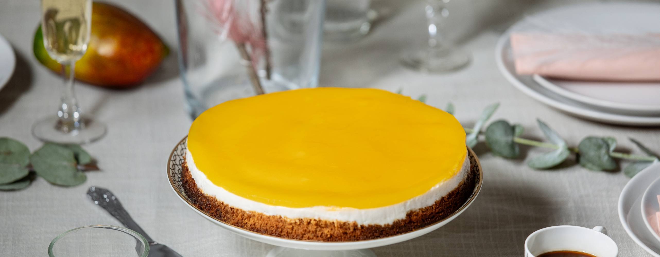 Foto: Melina Reid och Retouch: Linnea Herner Vegansk cheesecake med mangoglasyr på ett tårtfat.