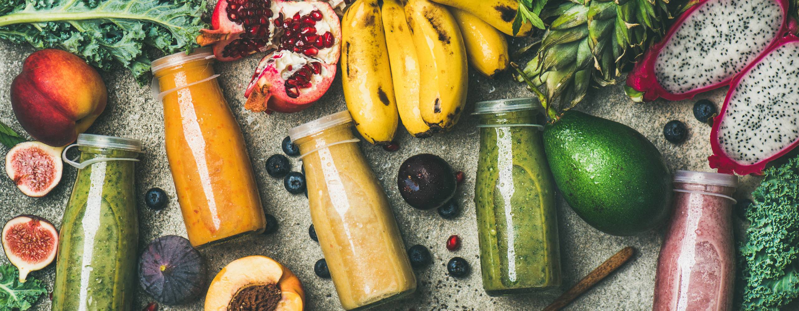 Diverse frukter och juicer i glasflaskor utspridda på ett bord