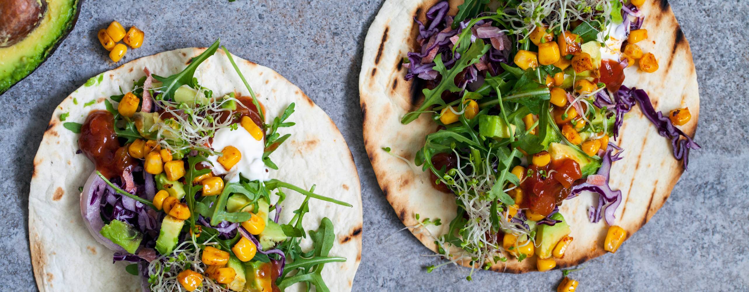 Öppna tortillabröd med grönt och pulled jackfruit på ett bord
