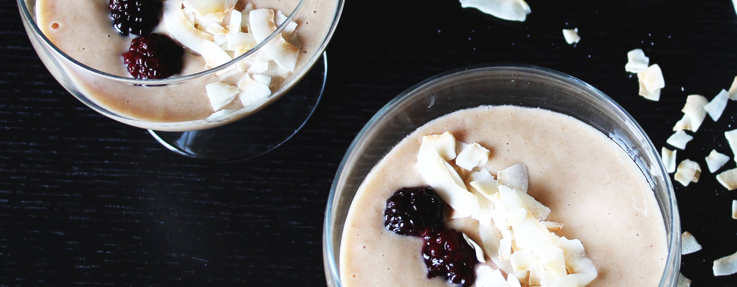 Två lucuma bowl i glasskålar, toppade med kokos och björnbär.
