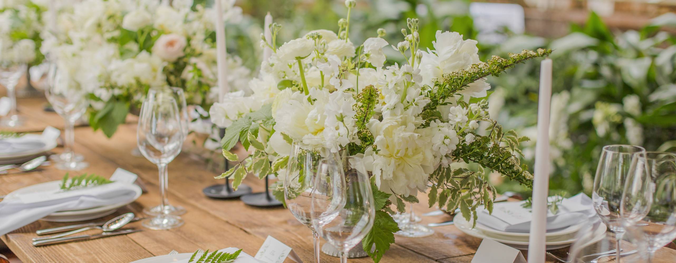 Ett bord som är findukad med vit porslin och vita blommor