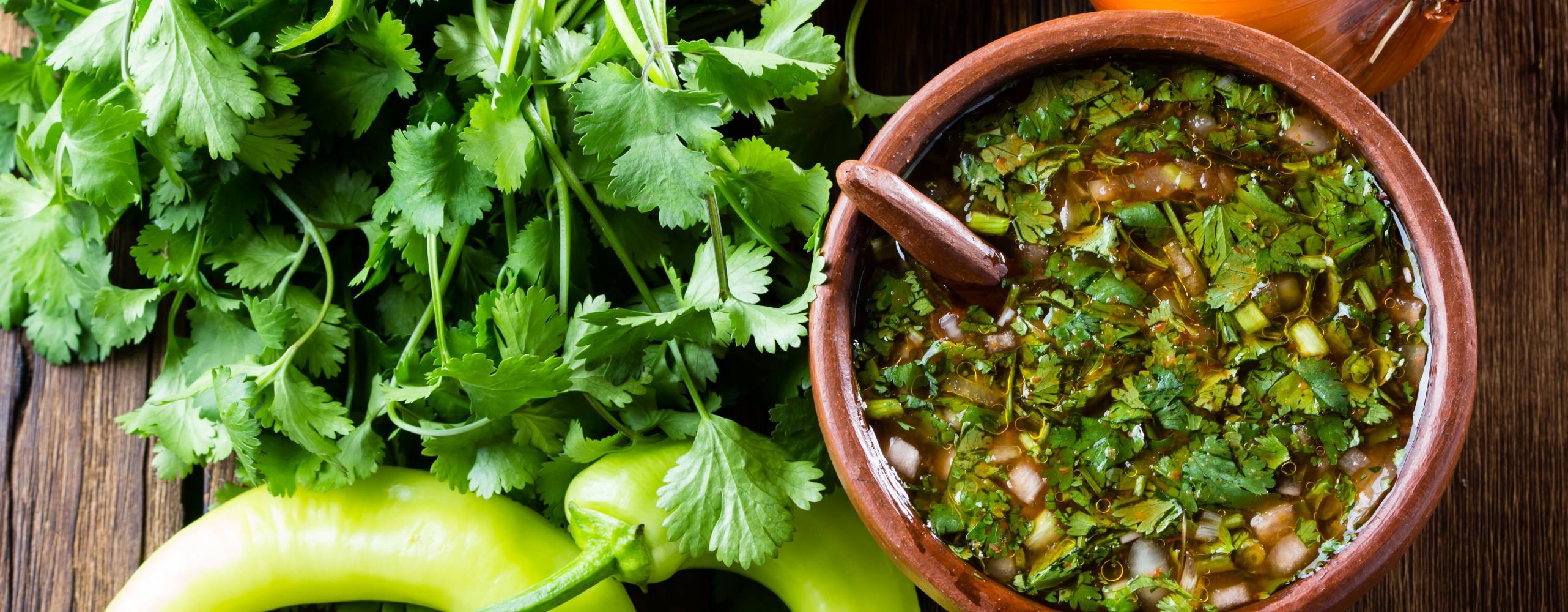 En skål med pebre tillsammans med lök, chili och koriander på ett bord