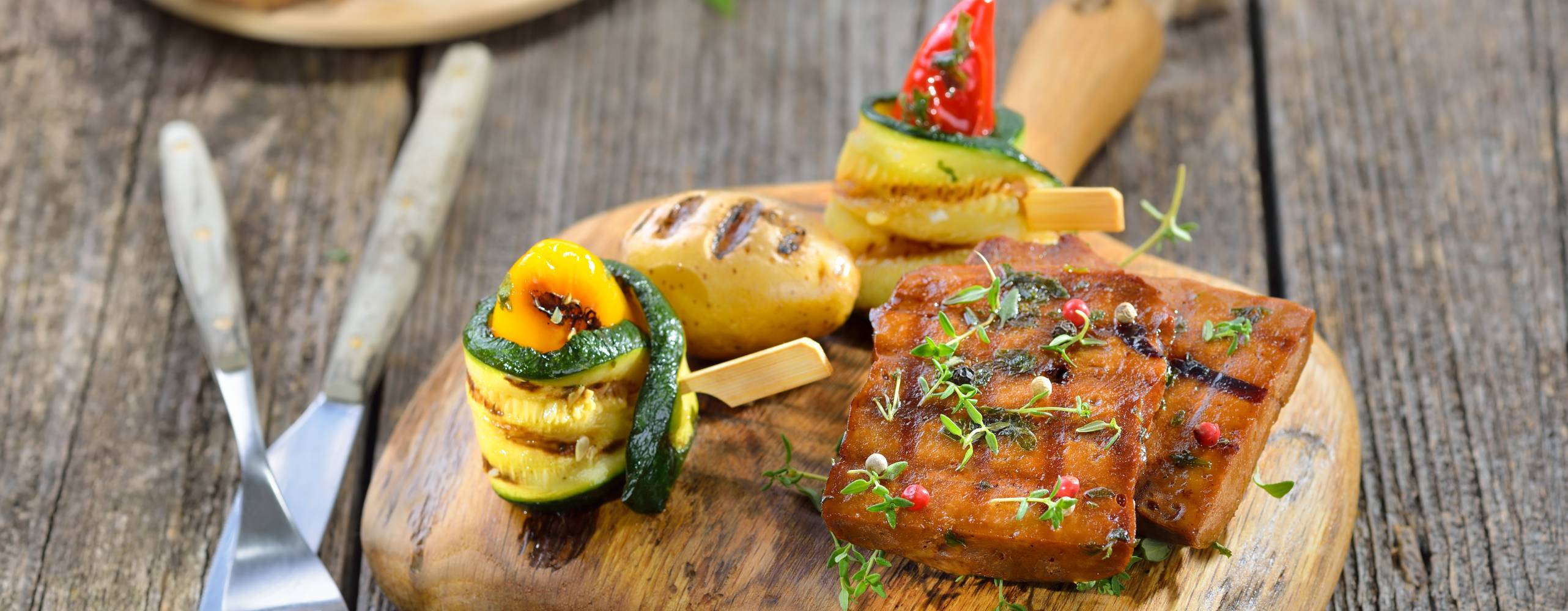 Vegansk seitan på en träbräda intill grönsaker