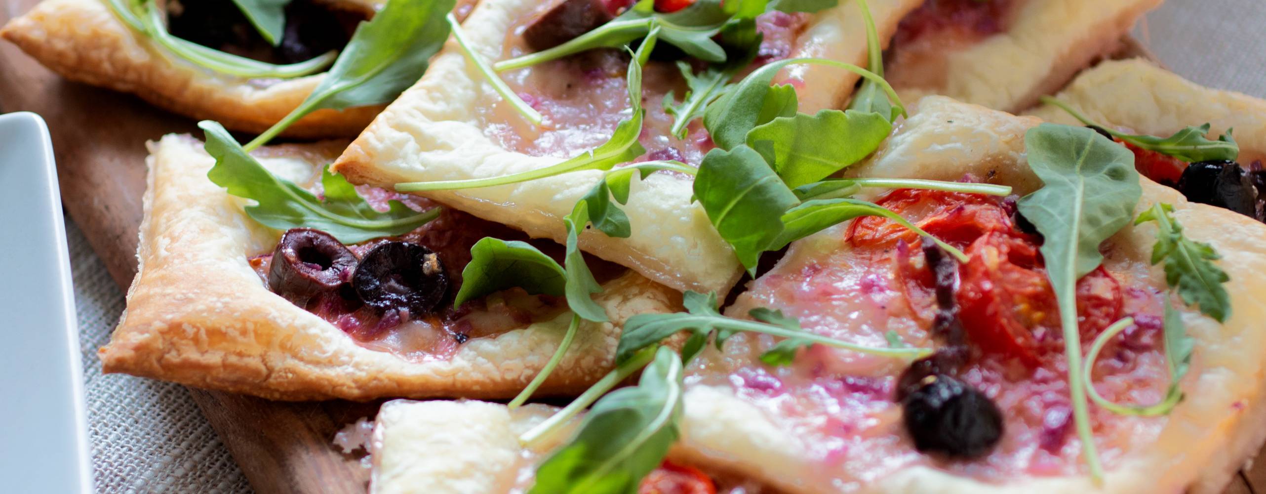 Smördegspaj med vegansk fetaost, oliver och tomat på en träbräda