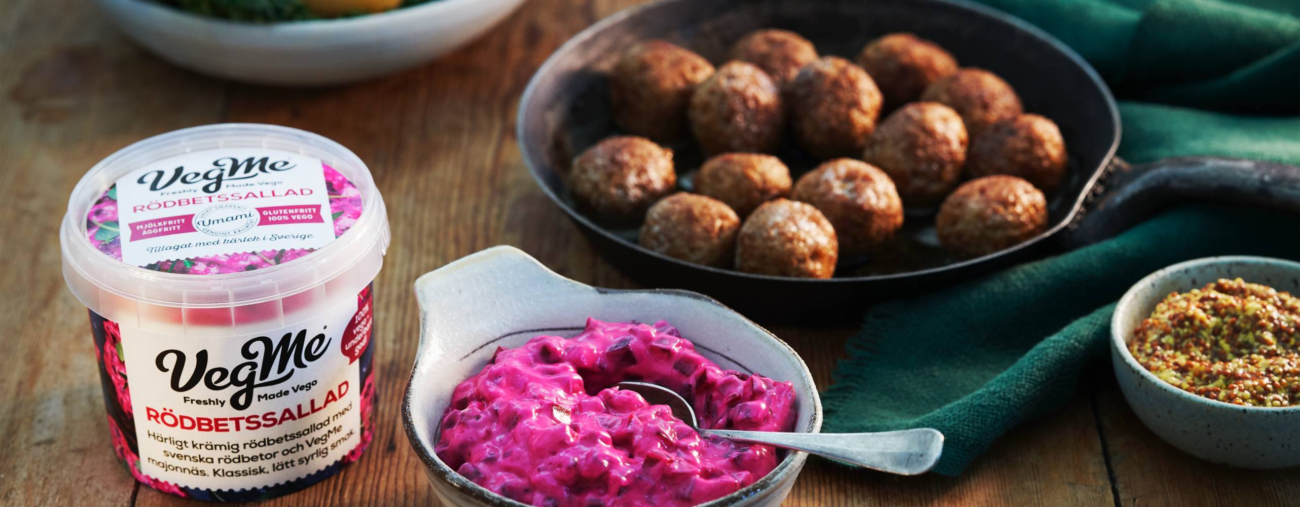 Förpackning på vegansk rödbetssallad från Vegme på ett bord intill vegobullar