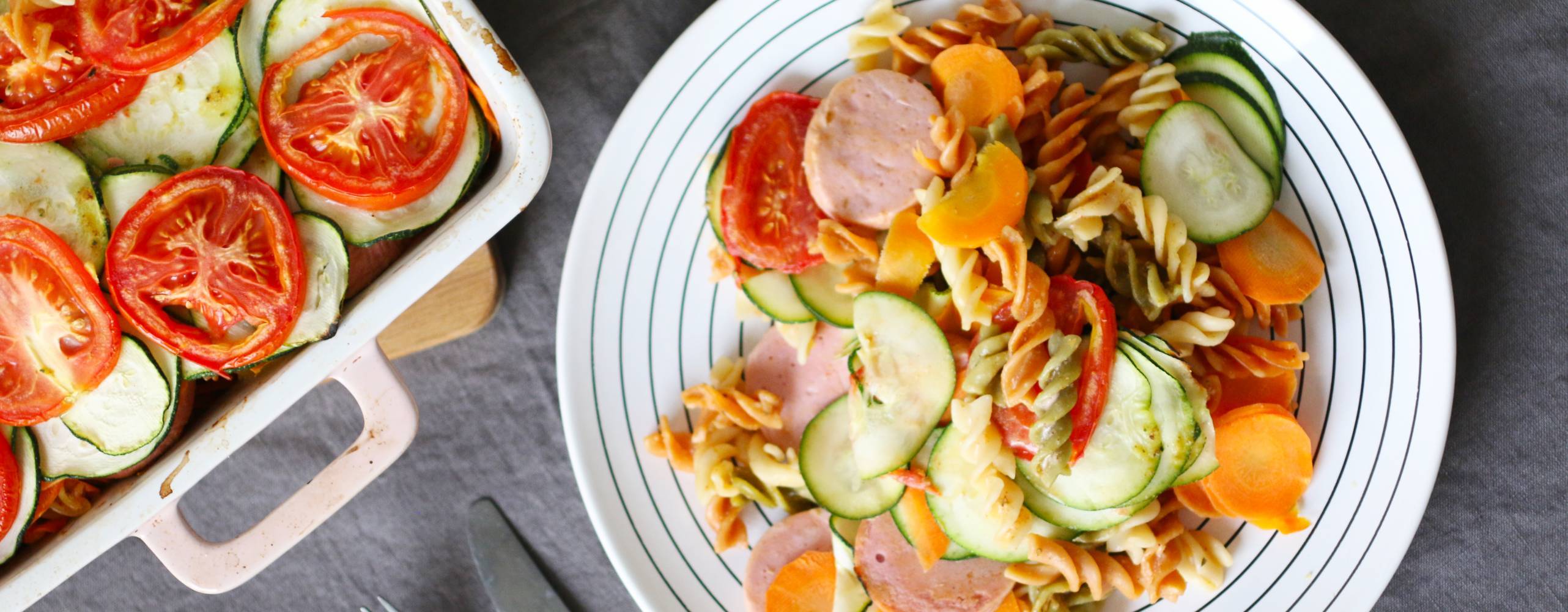 Vegansk pastagratäng på en tallrik intill en form med mer pastagratäng