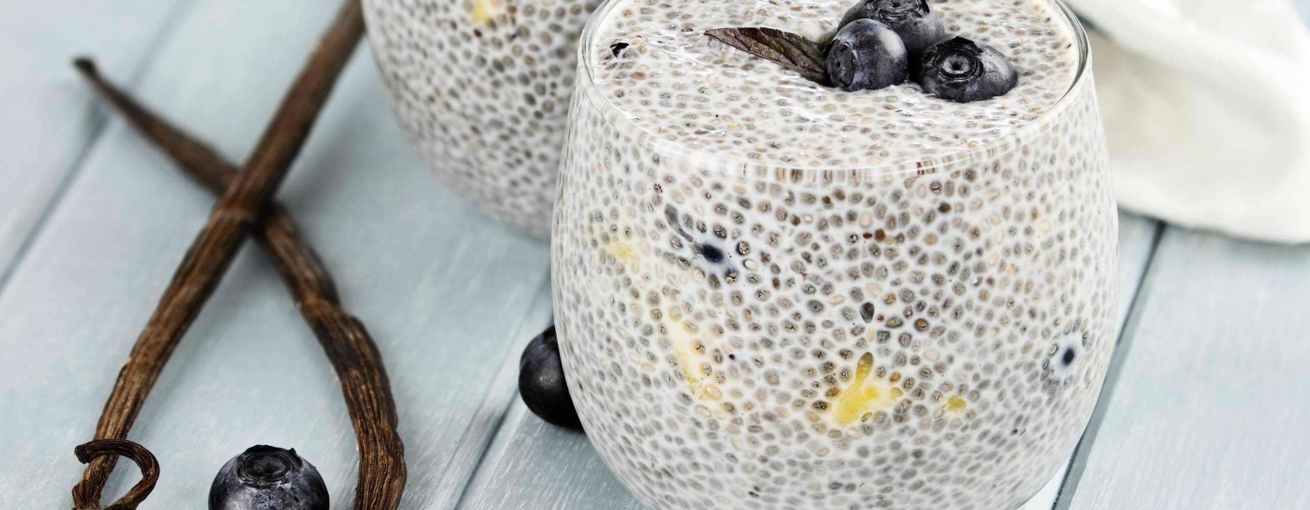 Chiapudding i ett glas med några blåbär på ett bord.