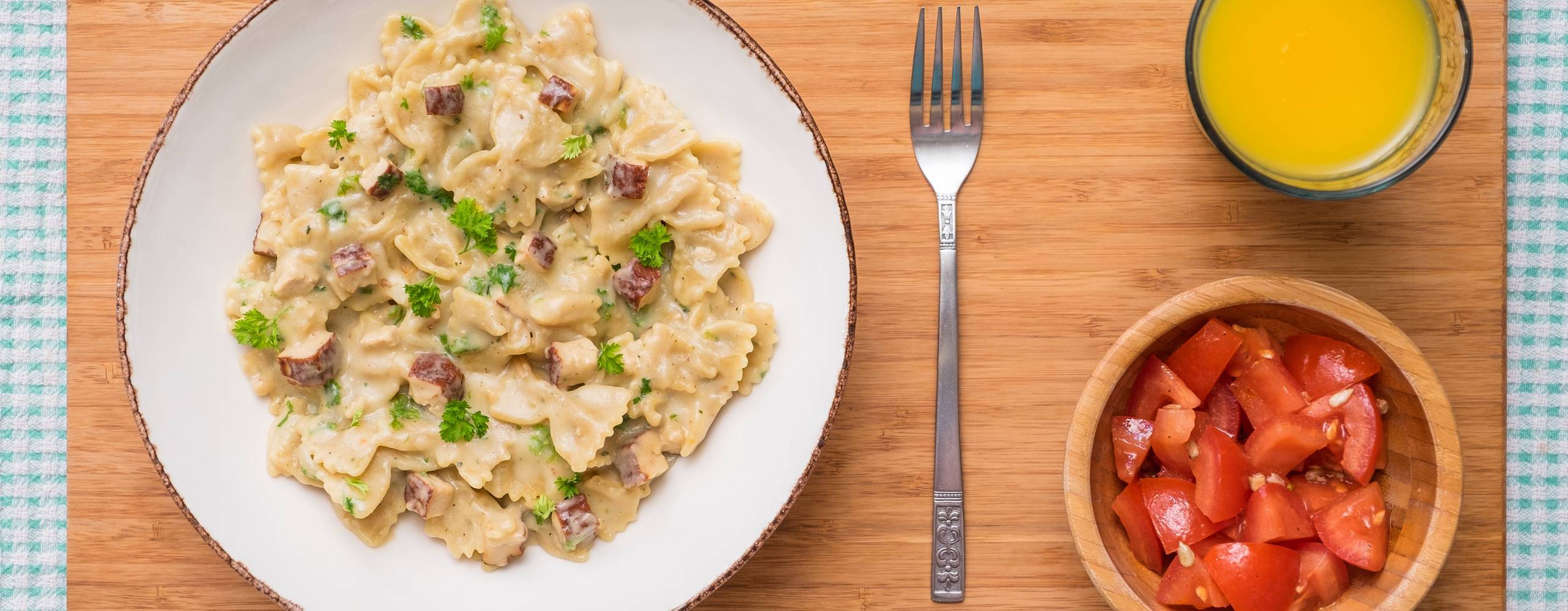 Vegansk carbonara med tofu på ett bord tillsammans med juice och tomatsallad