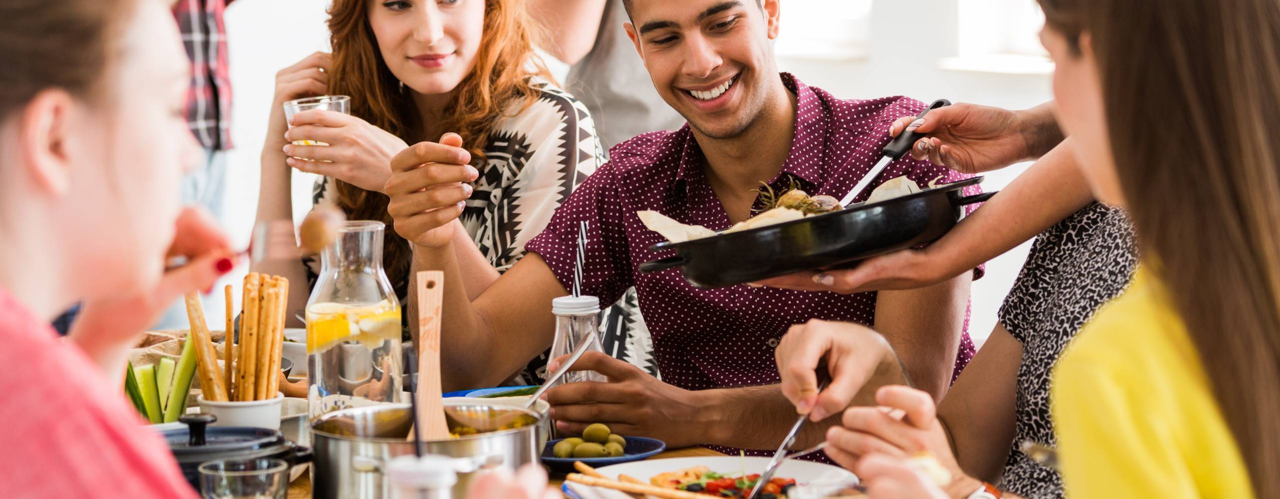 Ett gäng vänner samlade kring ett bord och äter veganskt mat