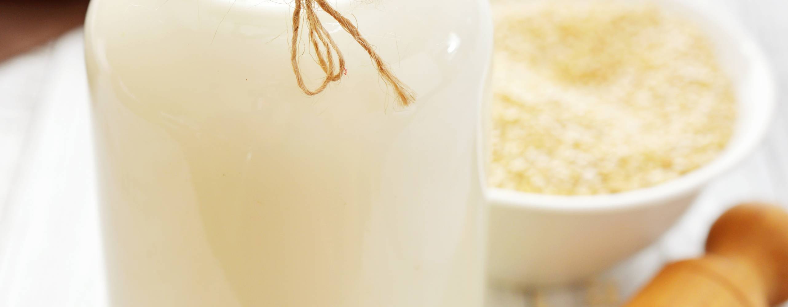 Växtdryck av quinoa i en glasflaska med vit quinoa på ett bord