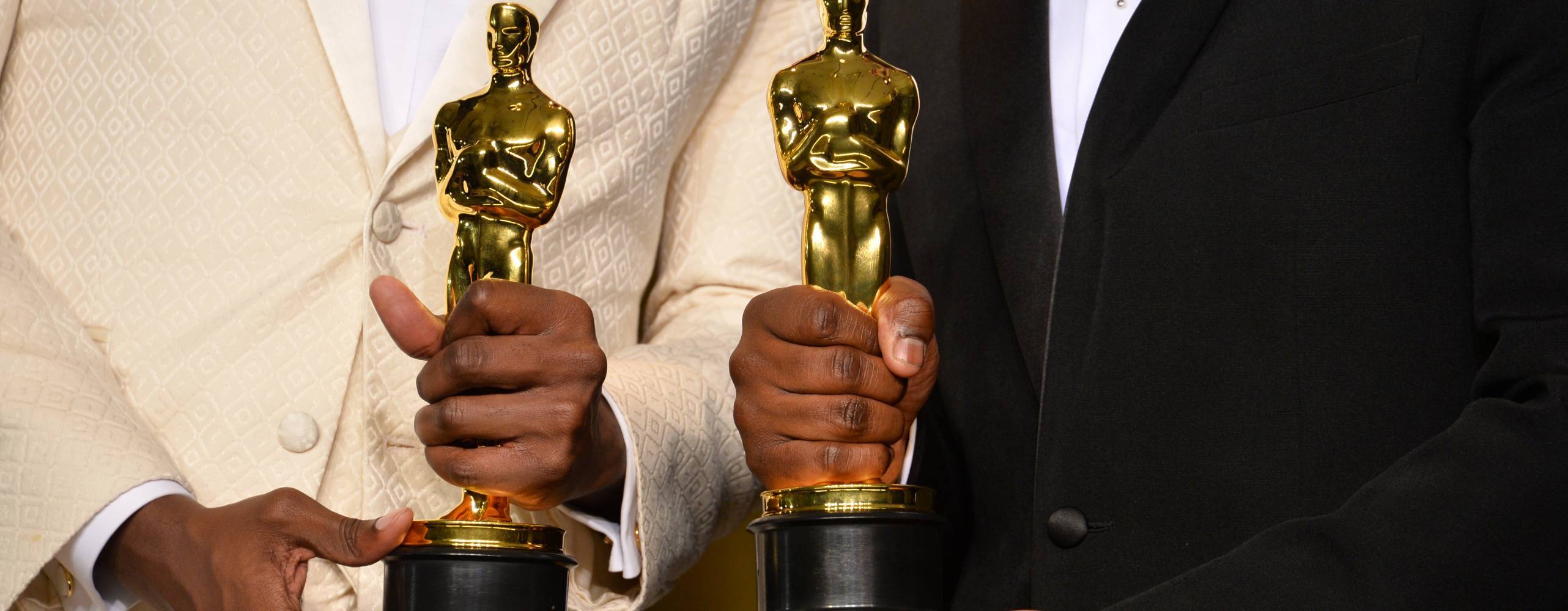 Två personer håller i varsin oscarstatyett