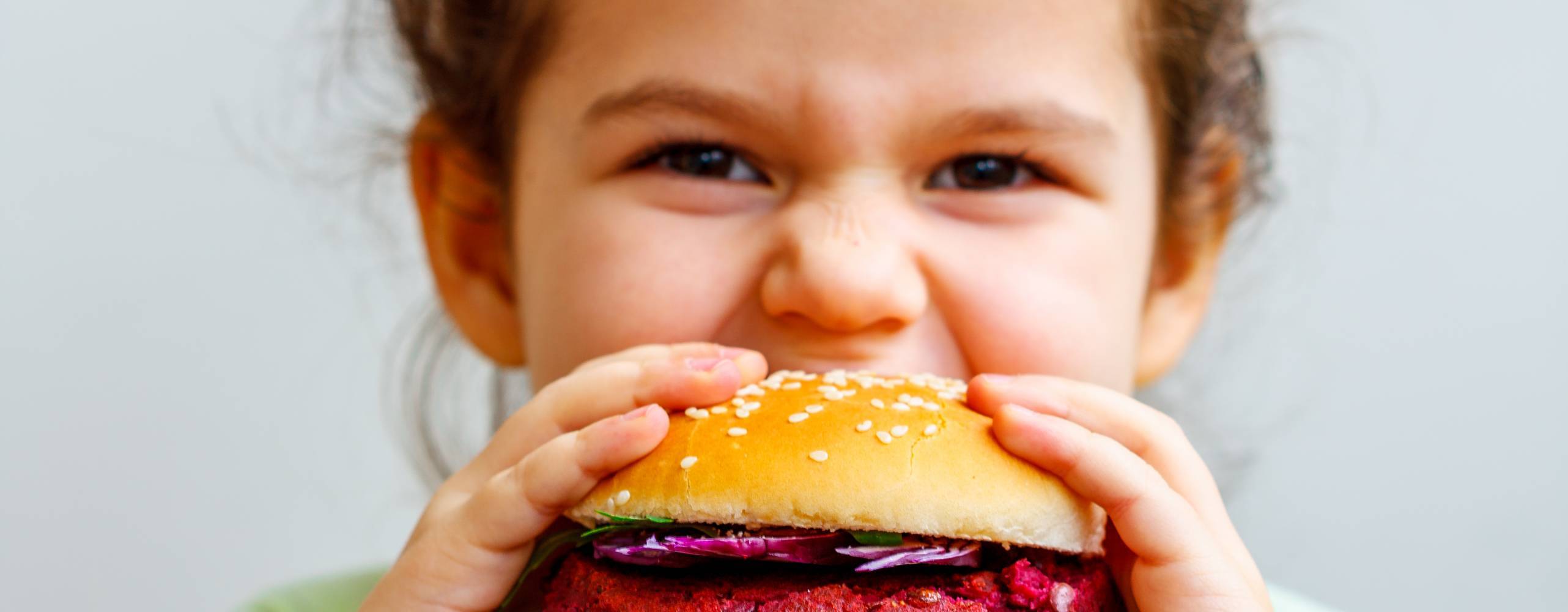 Ett barn tar en tugga av en vegansk burgare