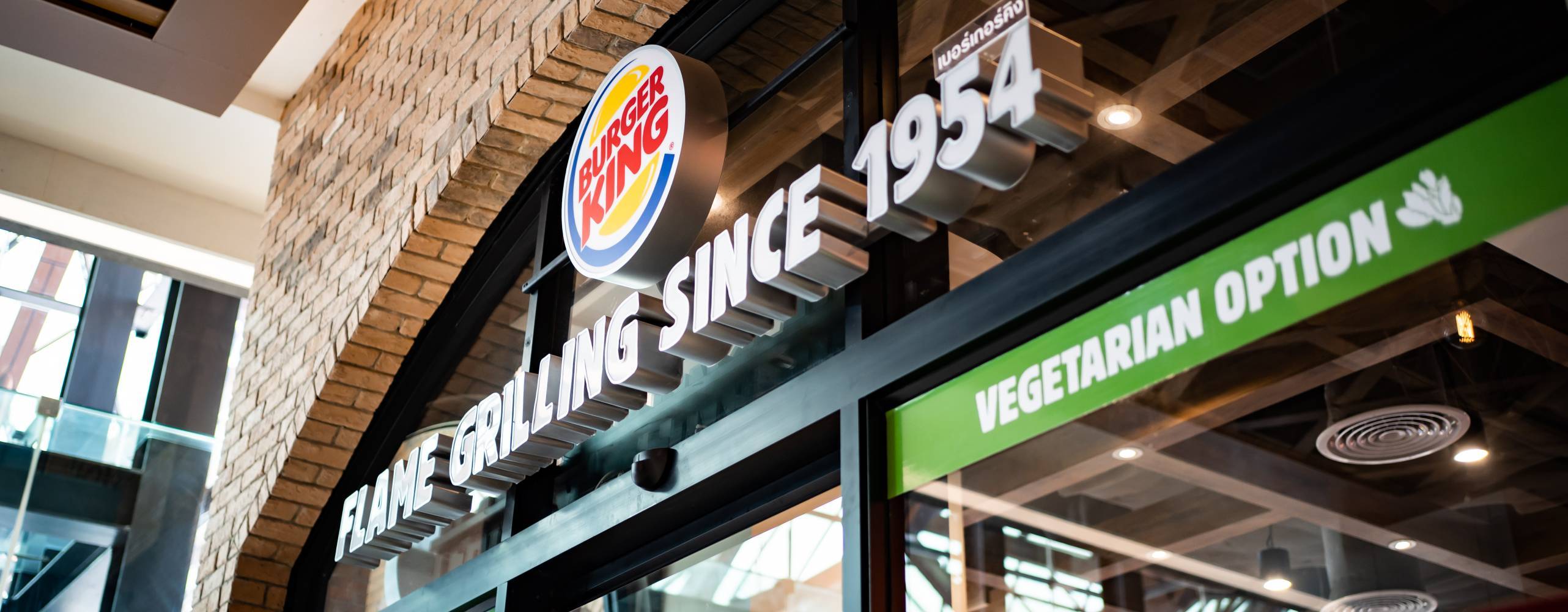 The label in front of the Burger King, hamburger fast food restaurant, showing that they have vegetarian option.