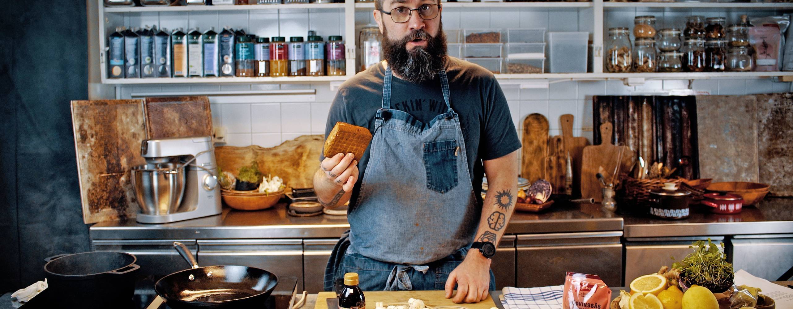 Fredrik Kämpenberg i ett kök med en tofu i handen