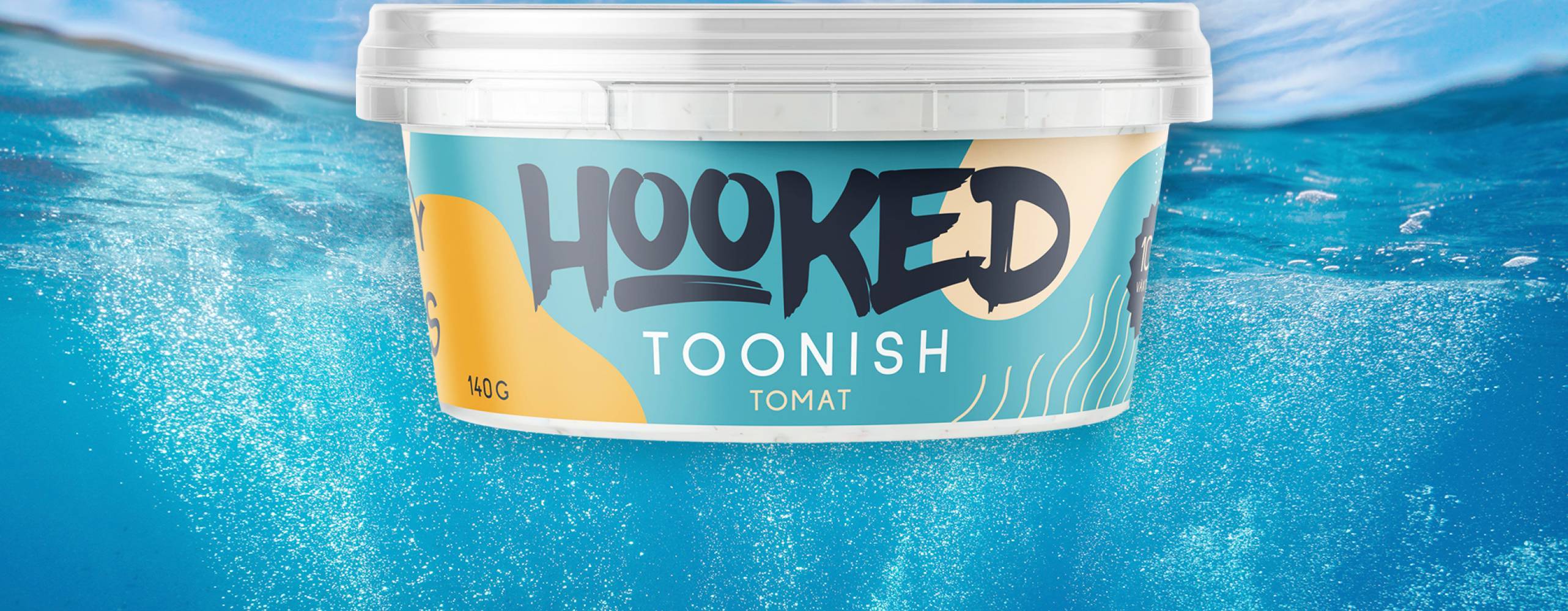 Produktfoto: Hooked foods / Bakgrundsfoto: Damsea/Shutterstock Plastburk med "Toonish" i smaken tomat mot bakgrundsfoto föreställande himmel och hab, taget delvis under vattenytan.