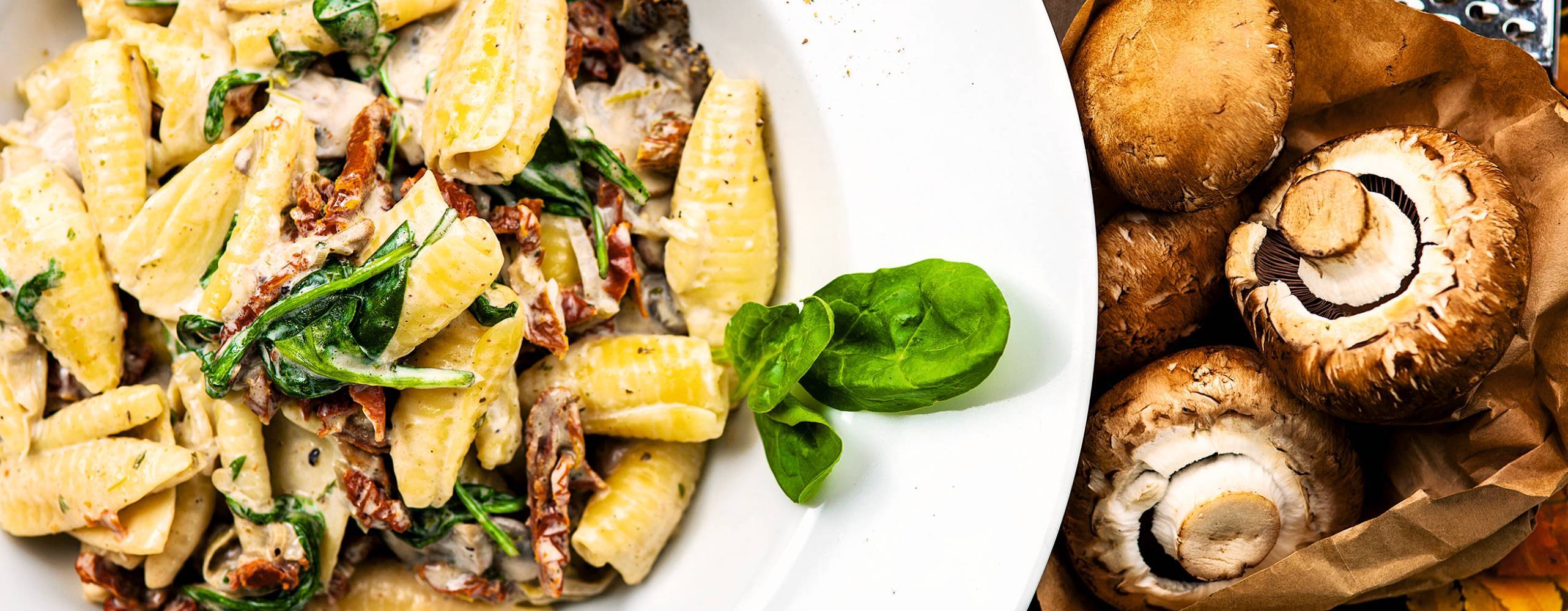 Krämig pasta upplagd i djup tallrik, med svamp och ost vid sidan av.