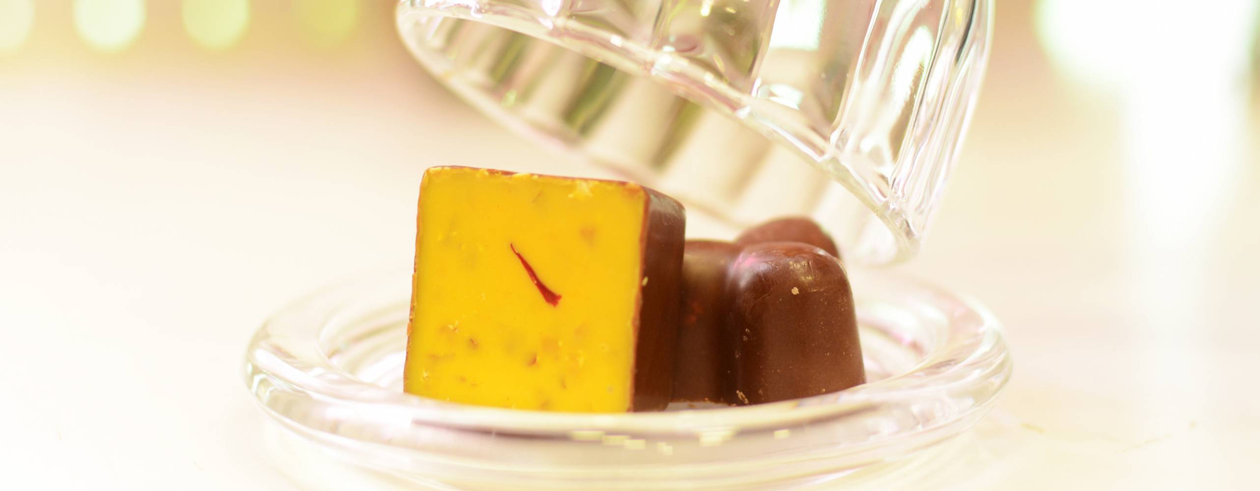 Chokladpralin med saffransfyllning på ett bord. En glaskupa lyfts undan.