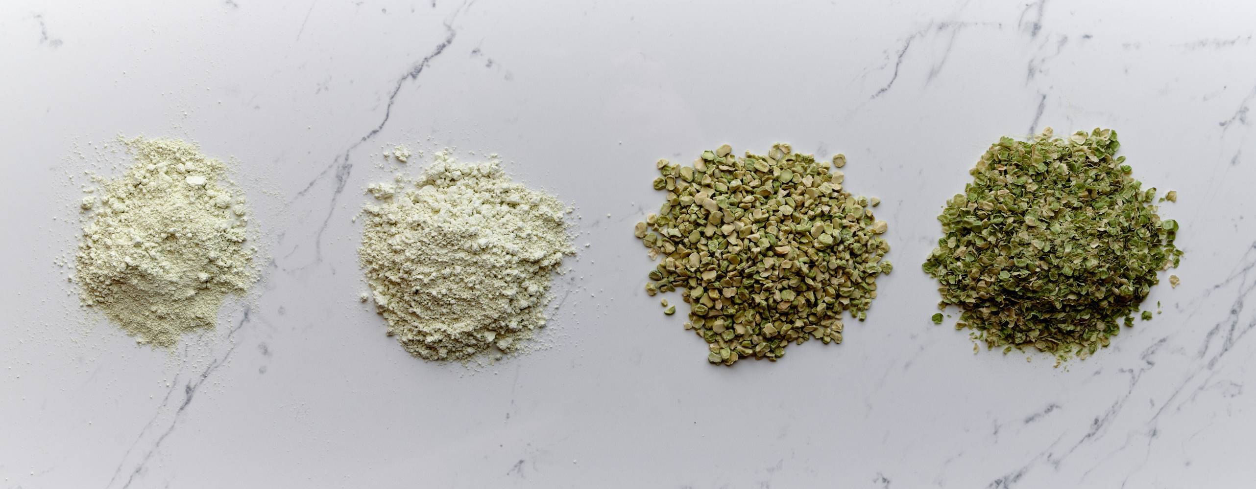 Ärtprotein i olika steg av förädlingsprocessen i små högar på marmoryta