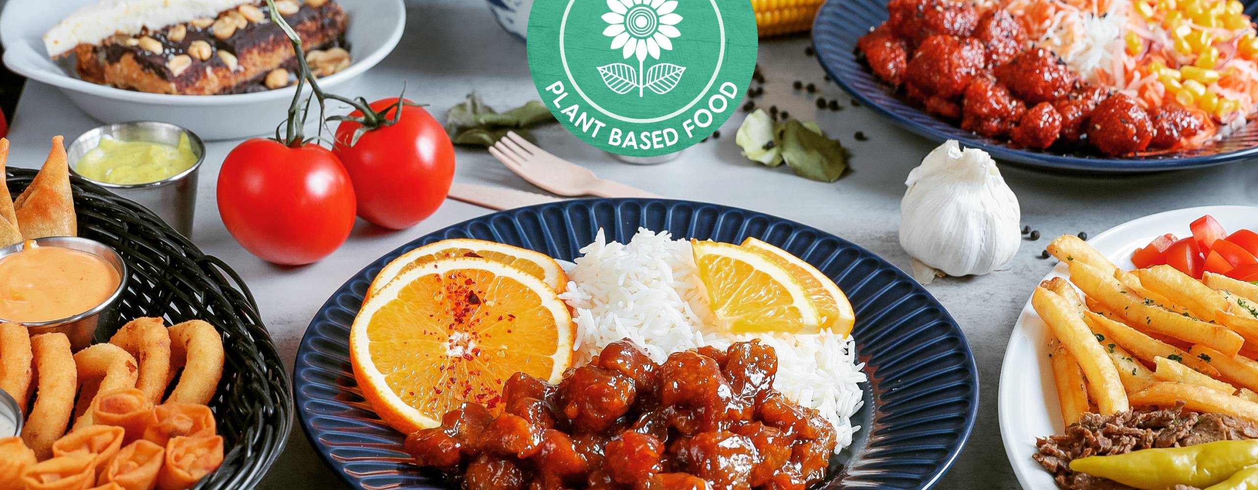 Maträtter från No Bones, uppdukade på ett bord med utspridda grönsaker som dekoration. PÅ bilden syns No Bones logga.