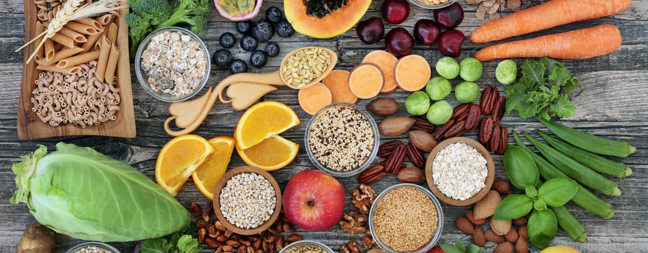 Veganska baslivsmedel, främst frukt och grönt, fotat ovanifrån på bordsyta.