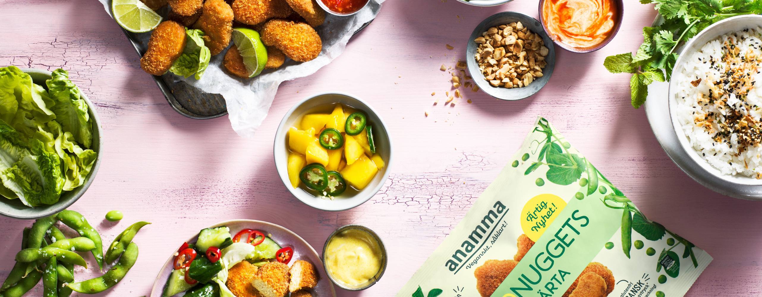 Växtbaserade nuggets i påse och uppdukade på olika sätt med mycket grönt på ett rosa bord.