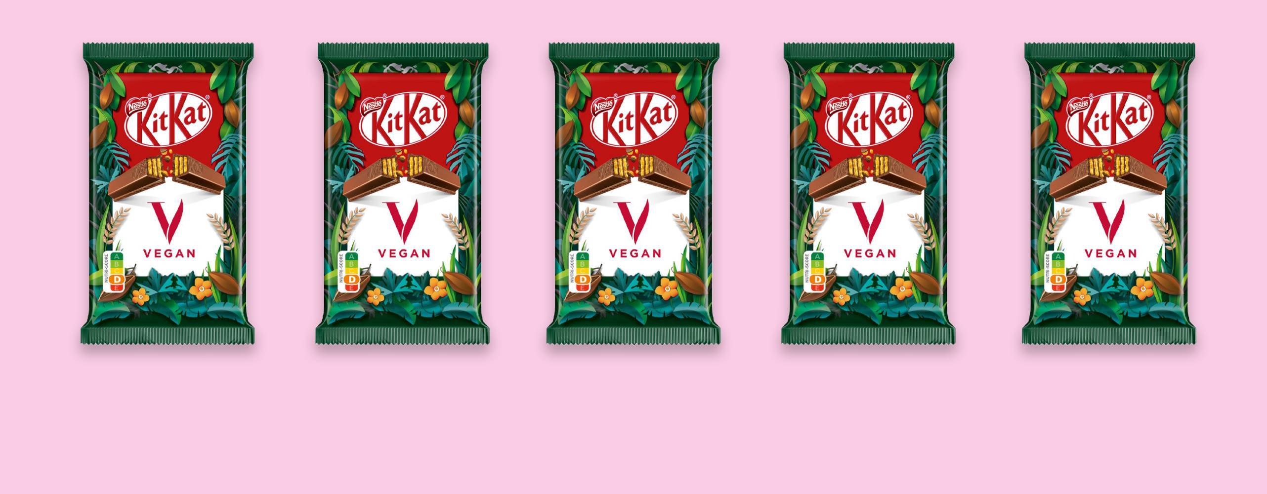 Fem veganska KitKat vegan uppradade mot en ljusrosa bakgrund.