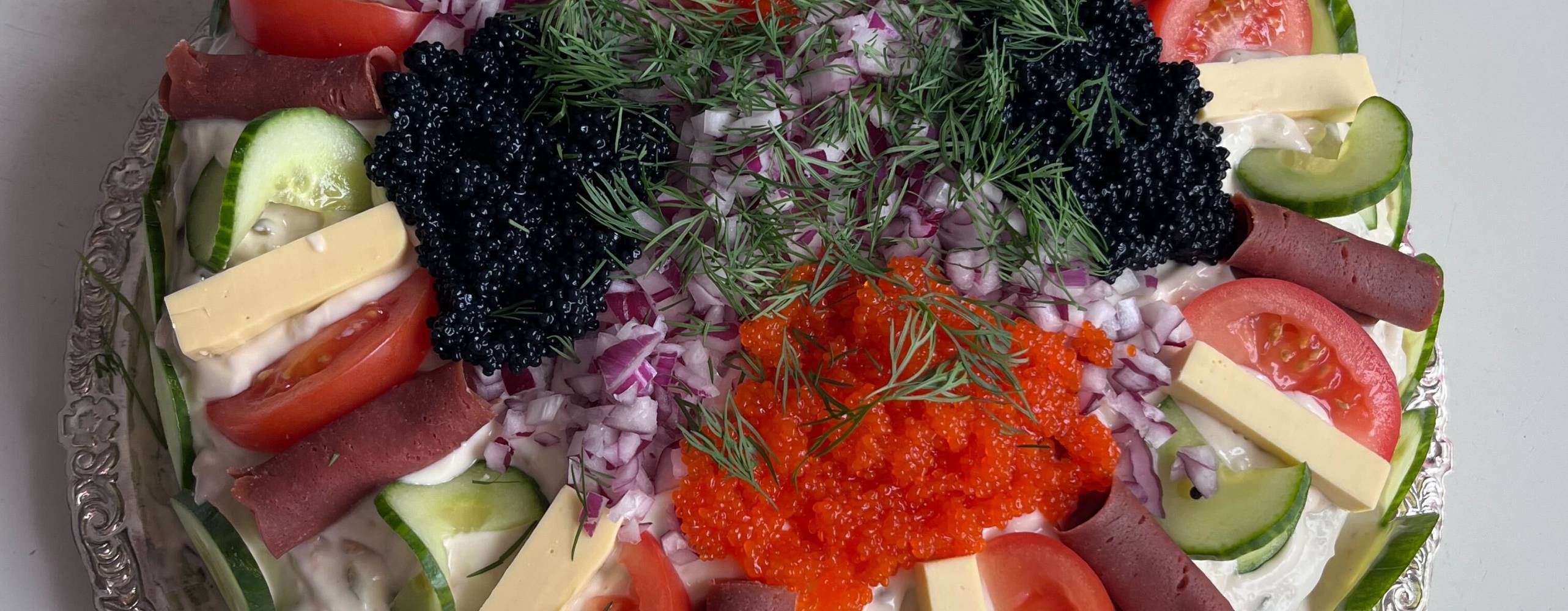 Vegansk smörgåstårta i rund form på ett silverfat.