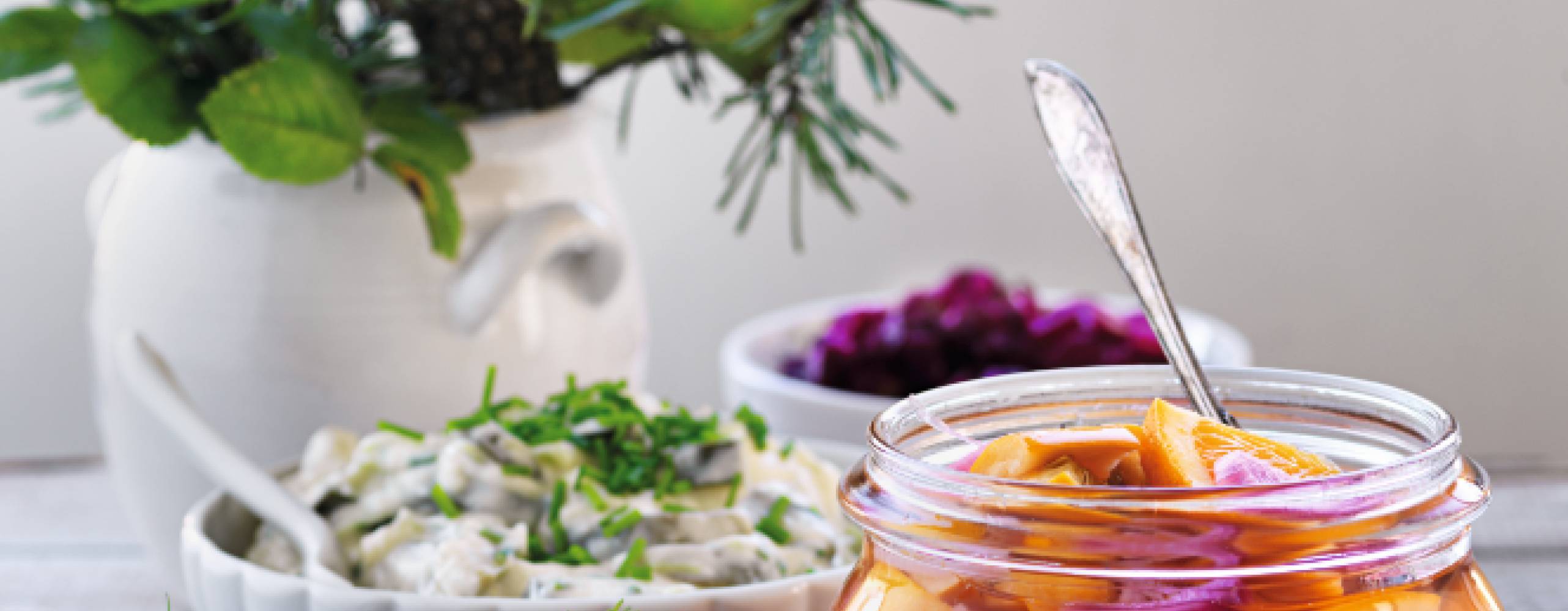 Picklad zucchini med apelsin i en glasburk bredvid snittar och vas med blomster